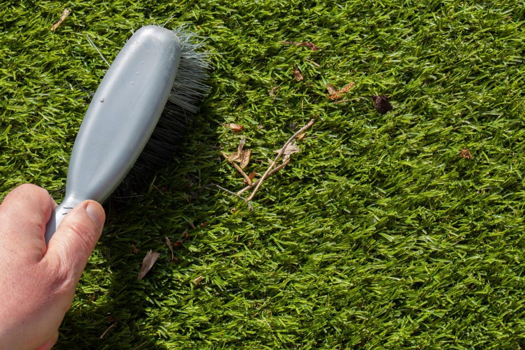 Maintaining artificial grass with a brush