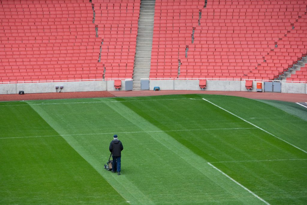 Person cutting the football pitch using a mower