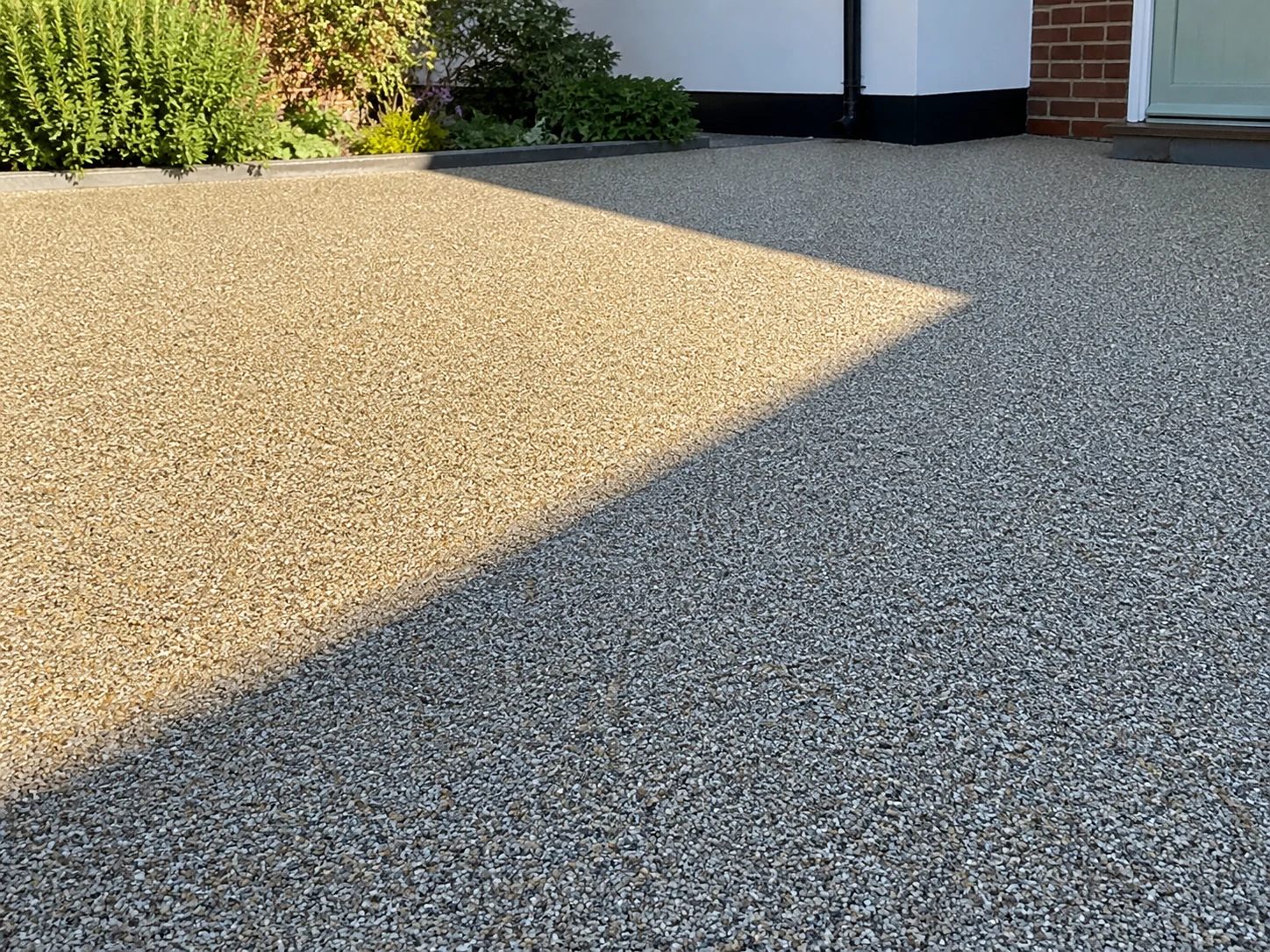 A resin driveway surface appearing different in sunlight and shade.